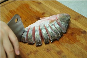 將鱸魚清洗干凈，從脊椎處切斷至腹部，腹部保留1cm左右不要切斷。