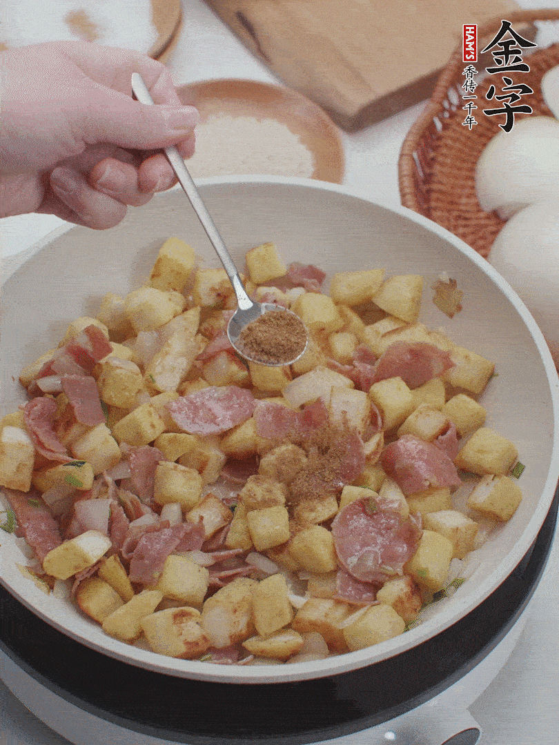 起鍋少油，煸香洋蔥丁、蔥白，加入金字培根火腿翻炒幾下，再加入饅頭丁、1小勺孜然粉、少許鹽翻炒均勻并鋪平。